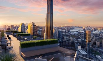 A rooftop terrace with a view of the city and a sunset